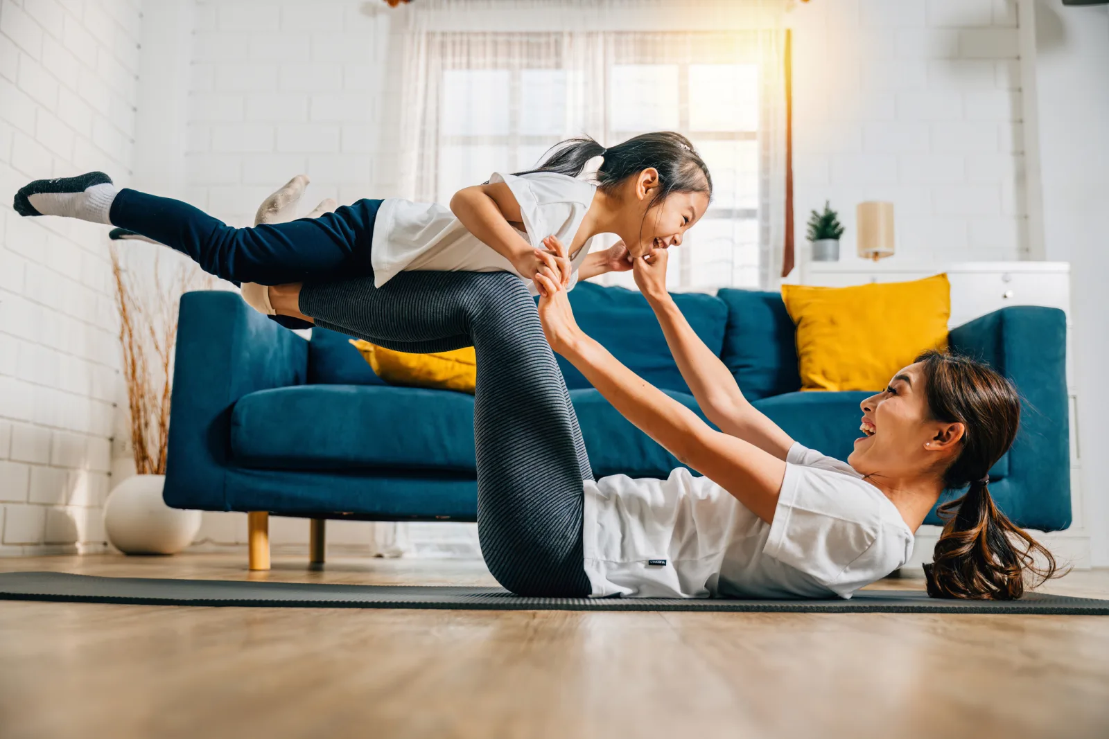 A mother and daughter exercising and playing together at home